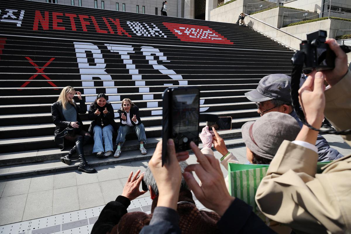 Fans of K-pop group BTS pose for photographs with an advertisement promoting 'BTS The Comeback Live Arirang' concert in central Seoul, South Korea, March 19, 2026.   REUTERS/Kim Hong-Ji