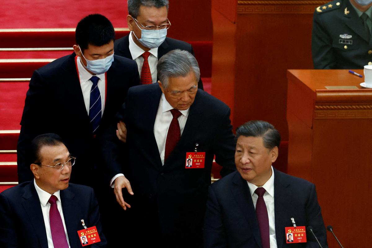 Former Chinese president Hu Jintao (centre) leaves his seat next to Chinese President Xi Jinping (right) and Premier Li Keqiang (left), during the closing ceremony of the 20th National Congress of the Communist Party of China, at the Great Hall of the People in Beijing, October 22, 2022. 