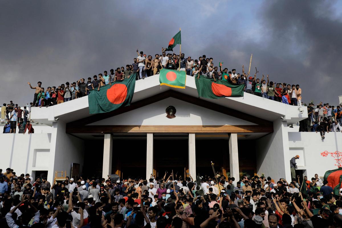 Anti-government protestors display Bangladesh's national flag as they storm Prime Minister Sheikh Hasina's palace in Dhaka on August 5, 2024. Anti-government protestors display Bangladesh's national flag as they storm Prime Minister Sheikh Hasina's palace in Dhaka on August 5, 2024.