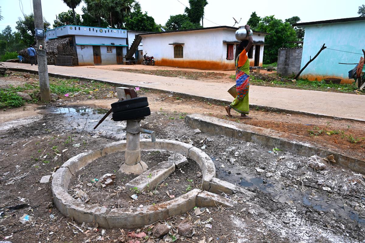 A woman carrying water walks past a defunct hand pump at Bhadrayyapeta village.