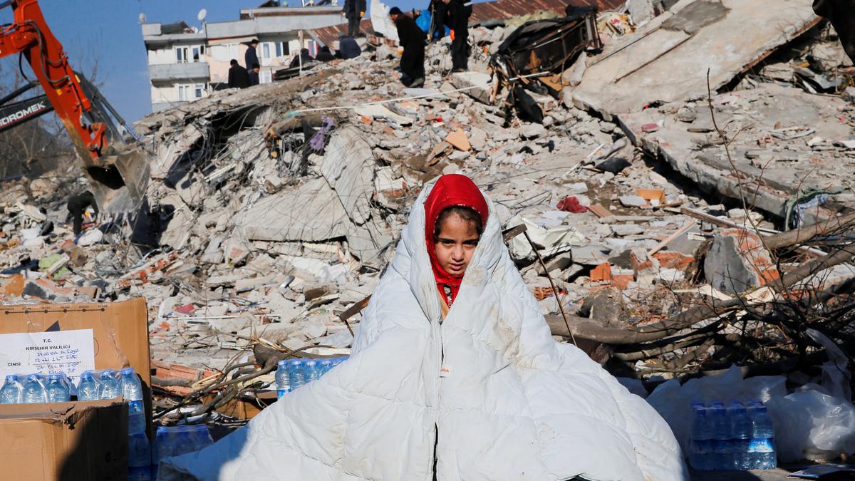 A girl sits near the site of a collapsed building following an earthquake in Kahramanmaras, Turkey.