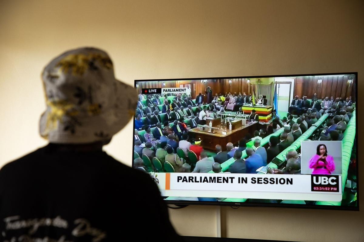 In this file photo taken on March 21, 2023, a Ugandan transgender woman who was recently attacked and is currently being sheltered watches a TV screen showing the live broadcast of the session from the Parliament for the anti-gay bill, at a local charity supporting the LGBTQ Community near Kampala. 