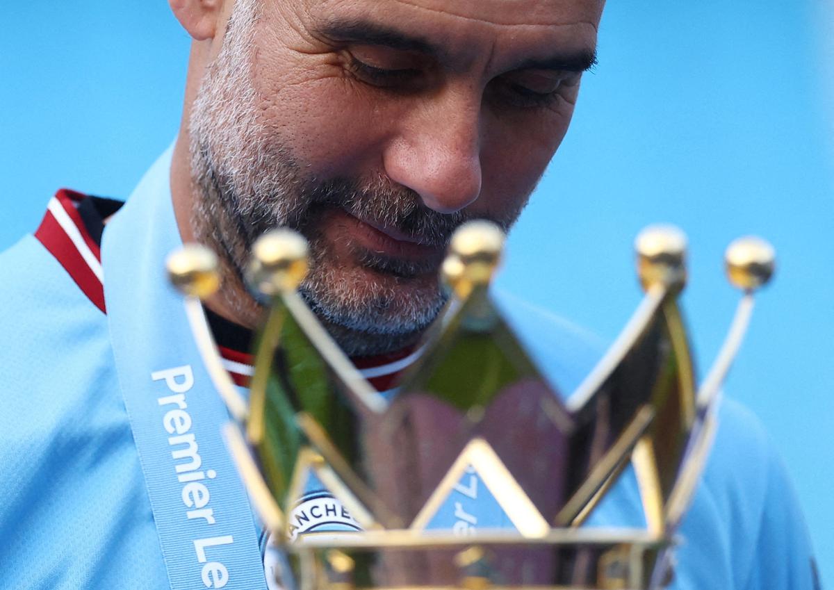 Manchester City manager Pep Guardiola celebrates with the trophy after winning the Premier League.