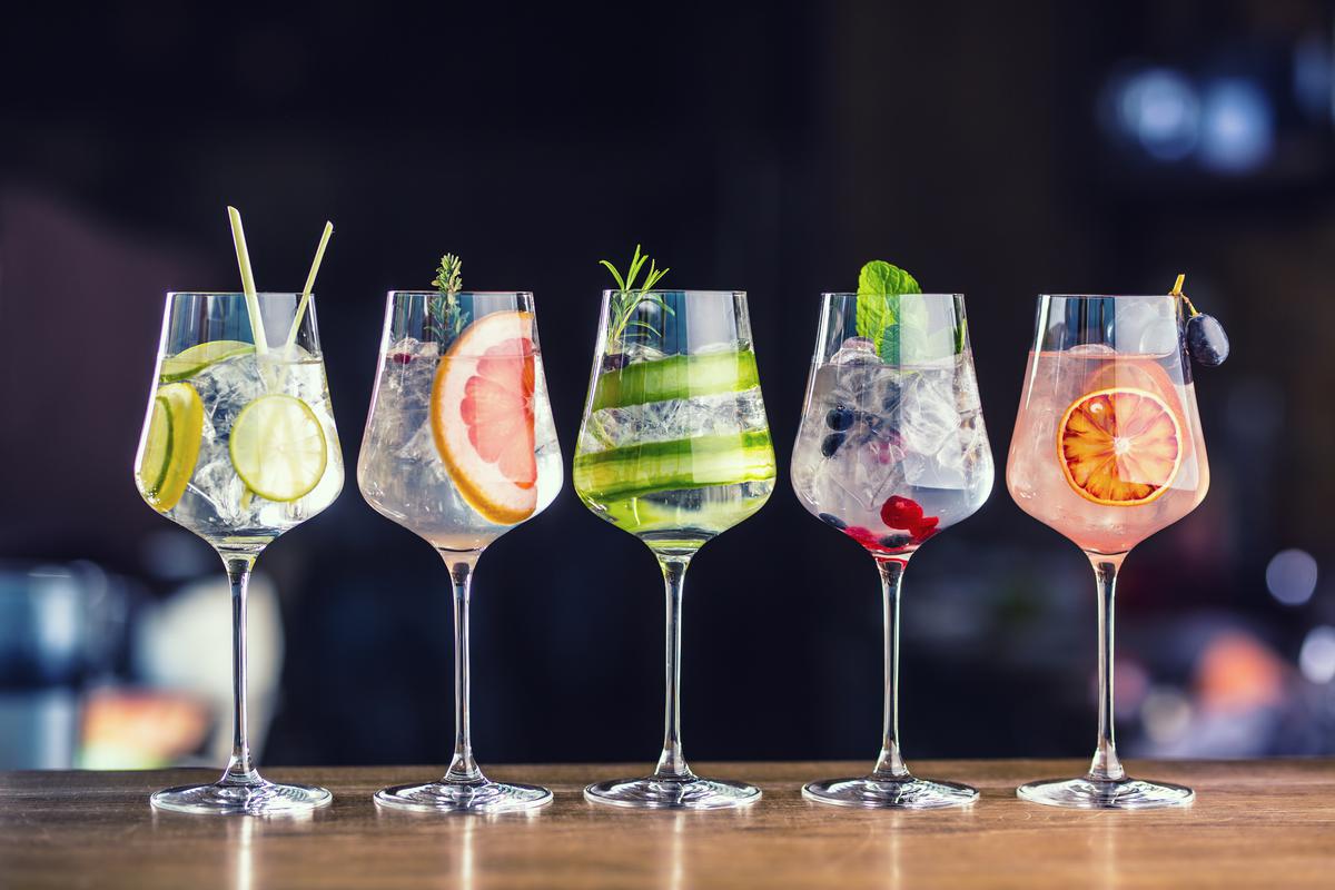 Five colorful gin tonic cocktails in wine glasses on bar counter in pup or restaurant. MP Food 