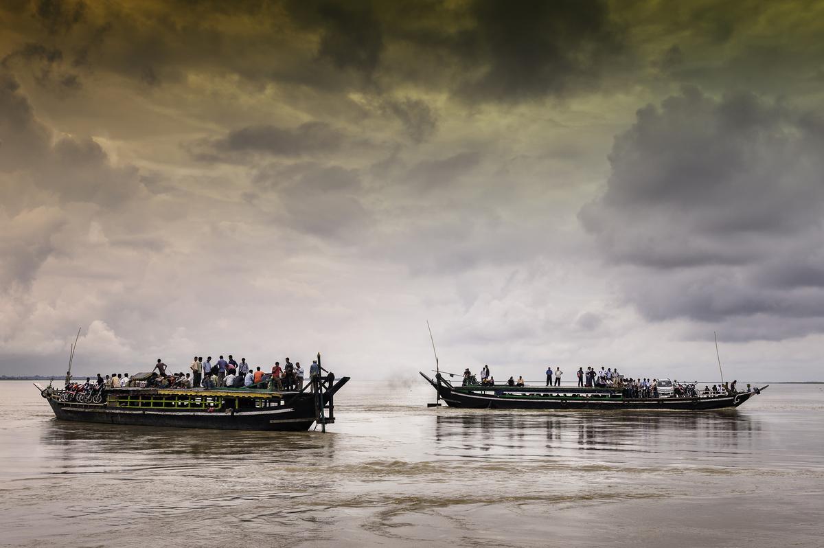 Overcrowded public ferries cross the Brahmaputra on a stormy day, in Assam.