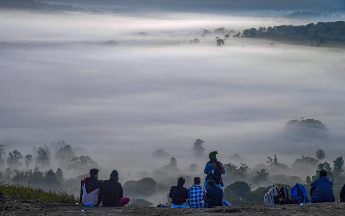 People enjoying a view of the fog engulfed valley on a cold winter morning in Araku.