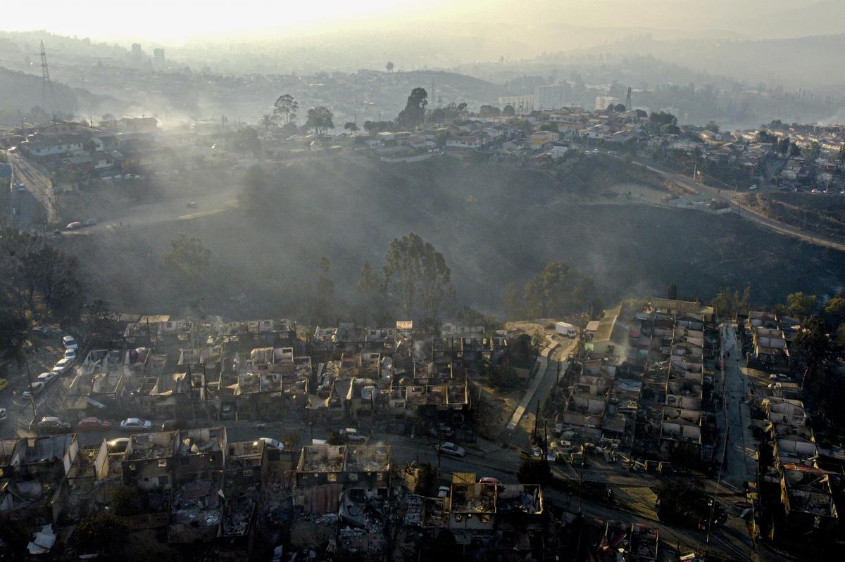 Smoke raises from burnt-out houses after a wildfire reached Villa Independencia neighbourhood in Vina del Mar, Chile, February 3, 2024. Scientists say climate change creates conditions that make the drought and wildfires now hitting South America more likely. 