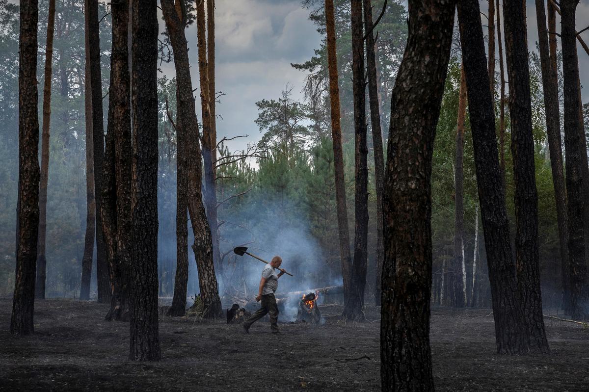 A worker carries a shovel he used to dig a firebreak to contain a forest fire near Yarova, Sviati Hory National Park, Donetsk region, amid Russia’s attack on Ukraine, July 29, 2024. Forest workers have been killed by landmines, booby traps and shelling during the conflict, according to environment ministry data.   