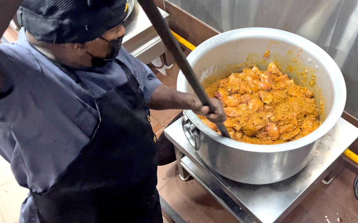 A cook mixing the masala and pieces of chicken at the central kitchen of Azad Hotel in Thiruvananthapuram. 