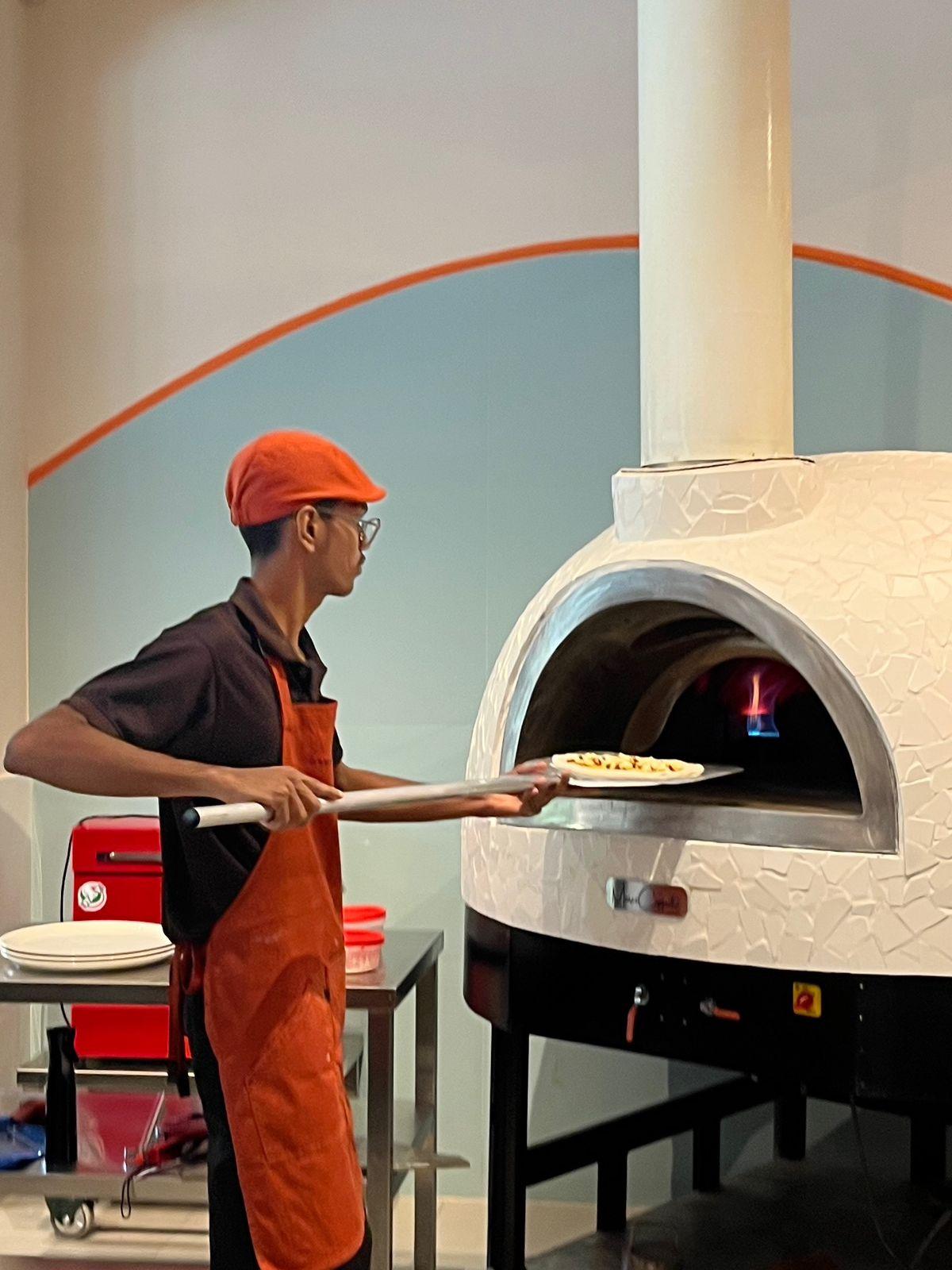 A pizza being popped into the oven