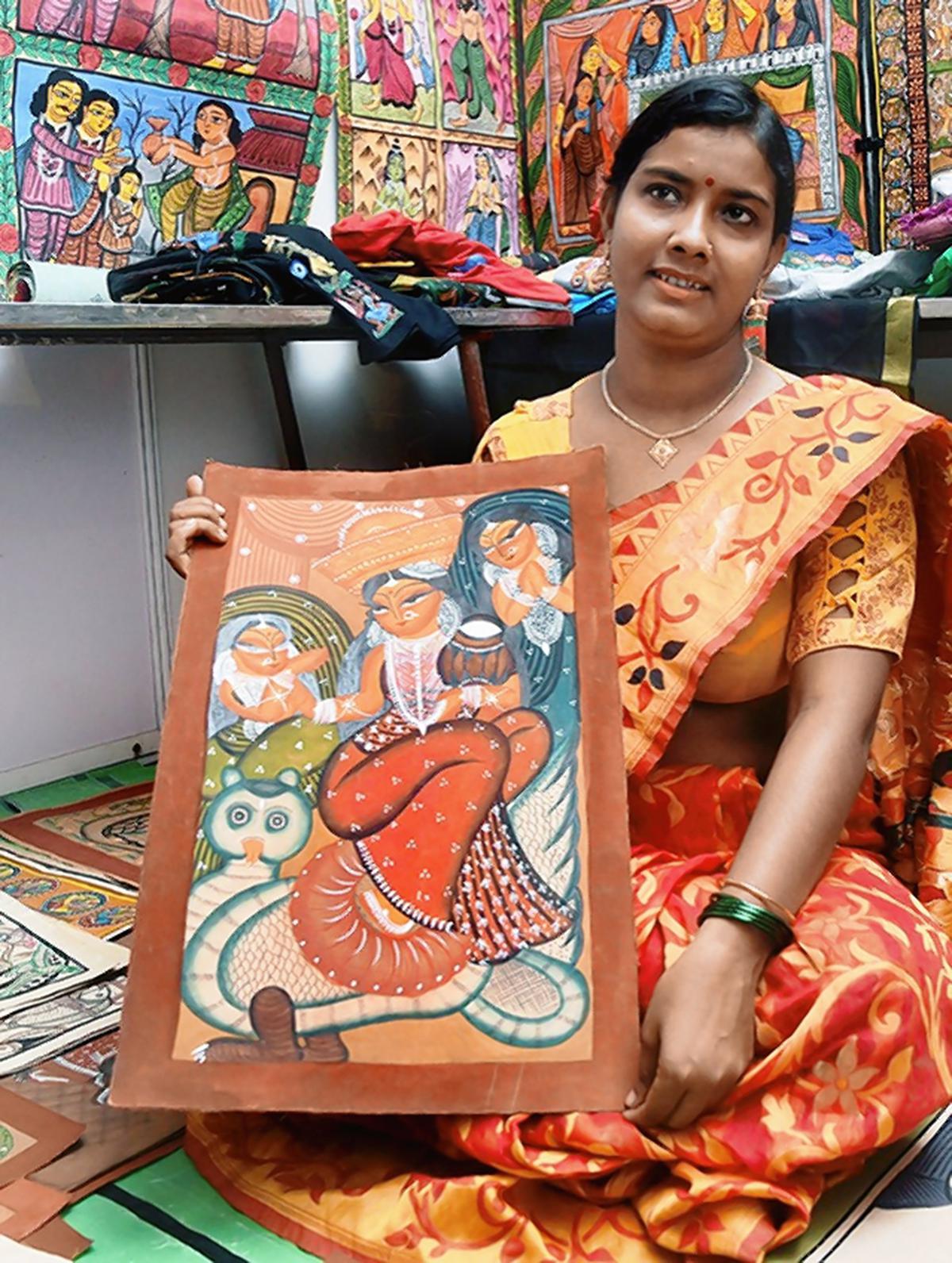 Rupsona, a pattachitra artist, with her scrolls