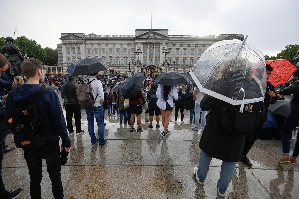 People shelter under their umbrellas as they gather outside Buckingham Palace, following a statement from the Palace over concerns for Britain’s Queen Elizabeth’s health, in London on September 8, 2022. 