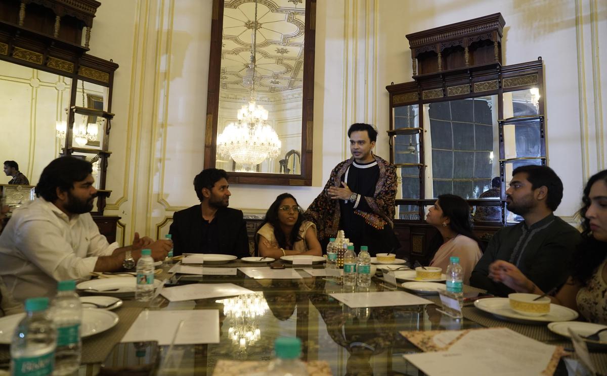 Aamir(standing)  with the guests seated for a royal dining experience at the Chowmahalla palace