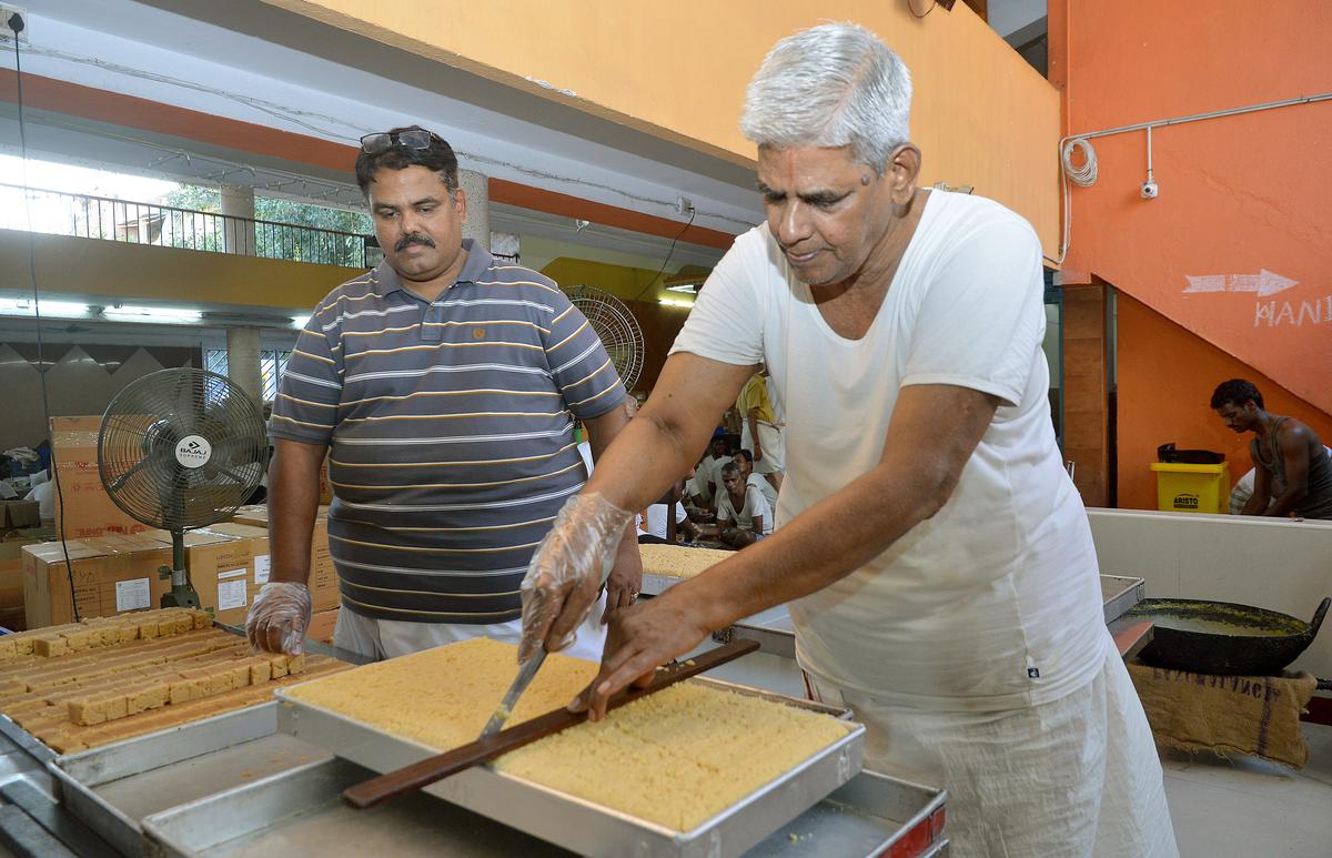 L.V.Pattappa (right) and his son slicing the mysore pak