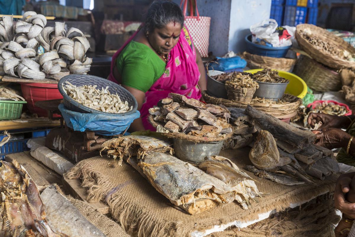 Een vrouw die gedroogde vis verkoopt op de markt.