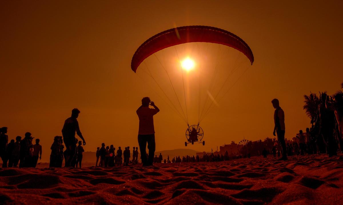 A paramotor landing on the beach in the backdrop of the sunset in Visakhapatnam.  
