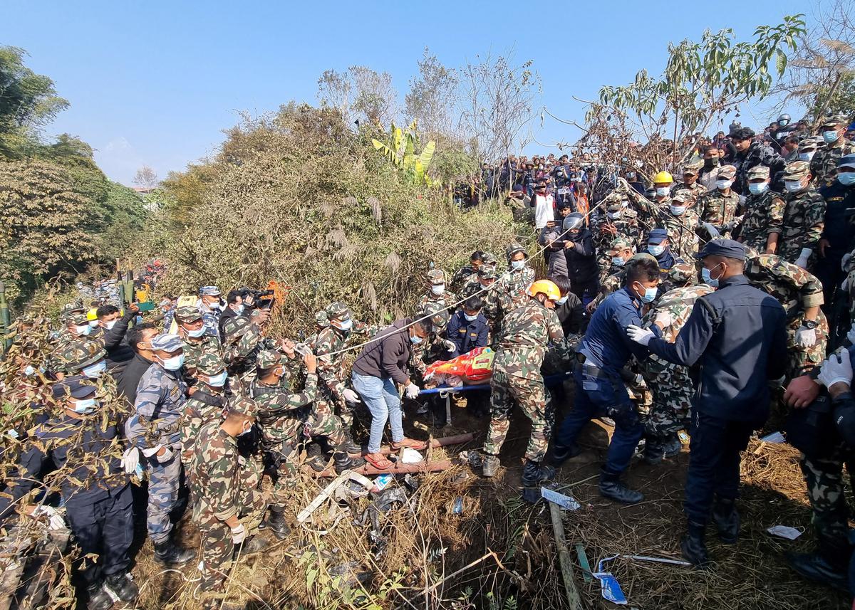 A rescue team caries a body of a victim from the crash site of the aircraft in Pokhara, Nepal.