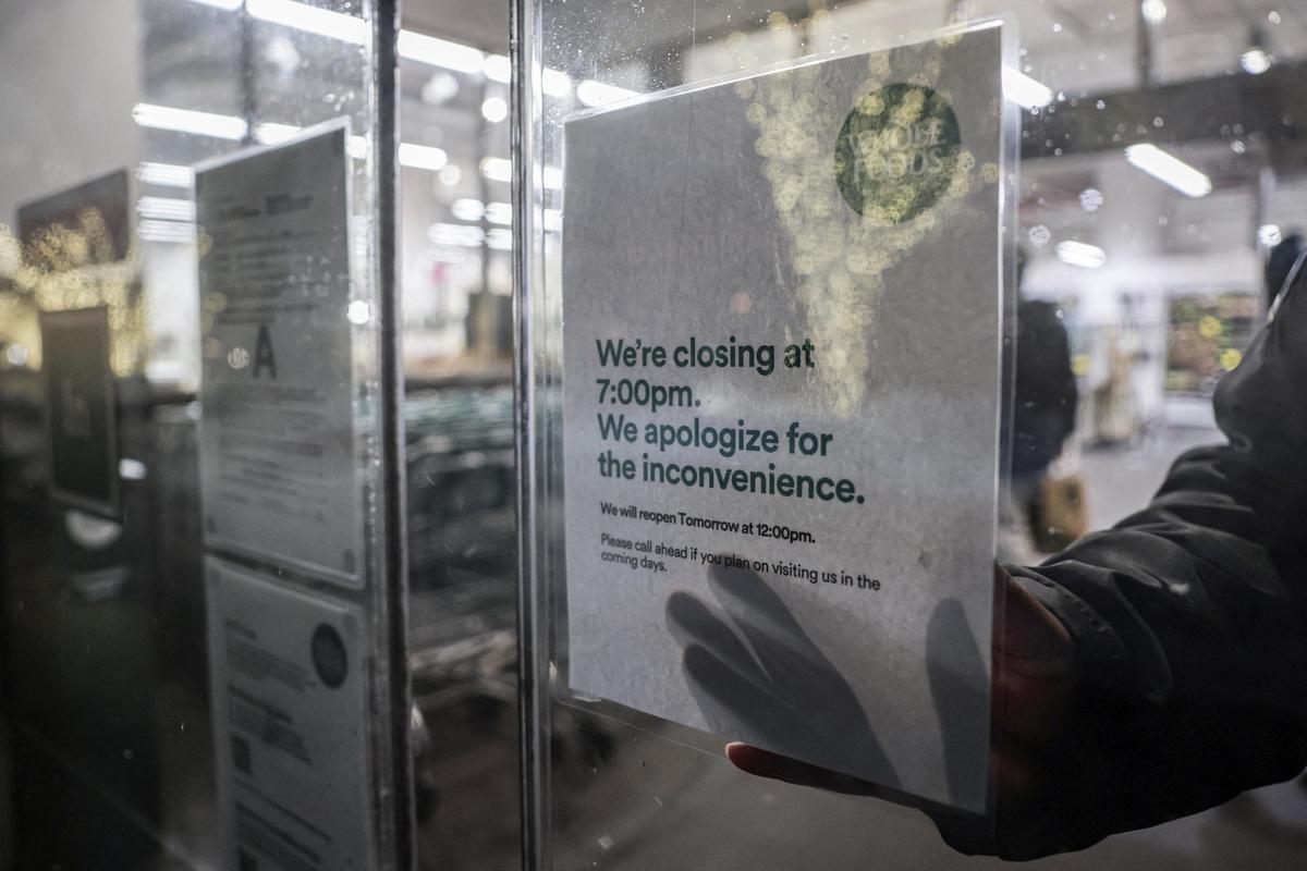 A closing sign is pasted on a door as snow falls during a winter storm in New York City, U.S., on February 22, 2026. 