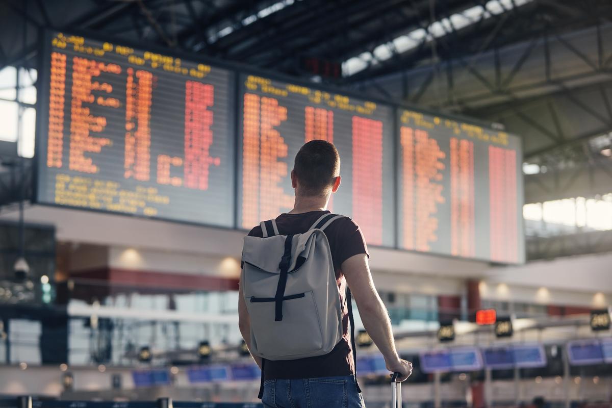 Man walking through airport terminal and looking at departure information