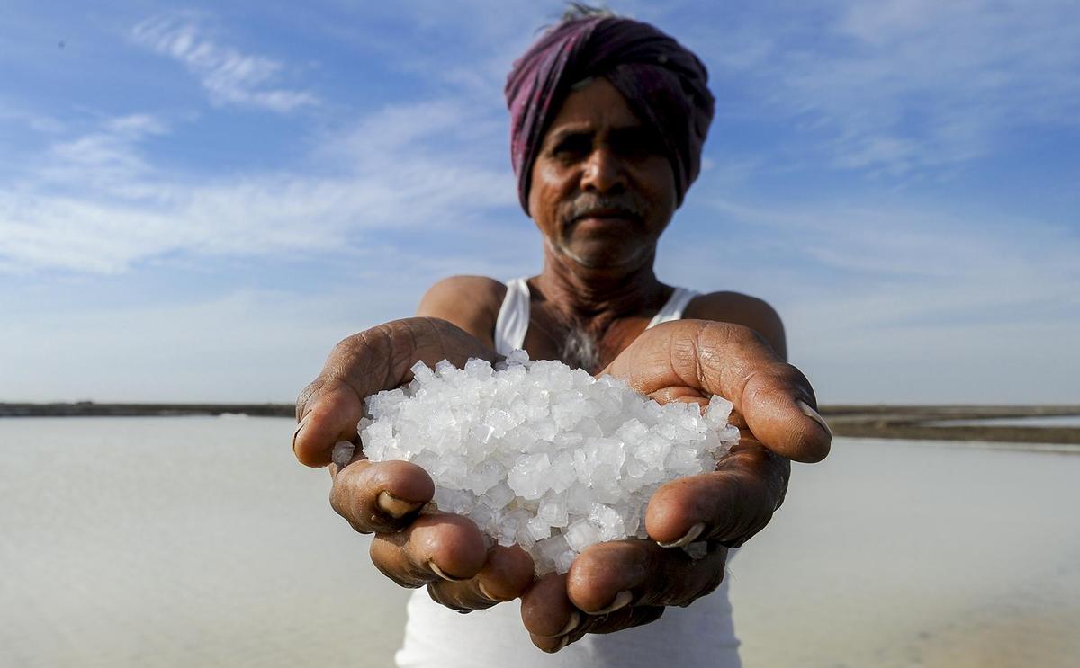A traditional salt pan farmer showing crystallised salt. People make a living here on salt farming.