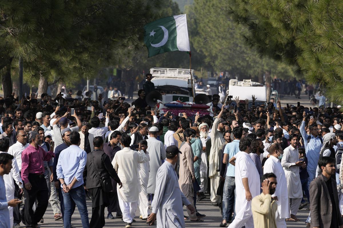 People walk with an ambulance carrying the casket of slain senior Pakistani journalist Arshad Sharif after his funeral prayer, in Islamabad, Pakistan, on Thursday.