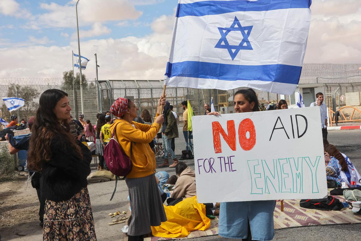 Israeli demonstrators gather by the border fence with Egypt at the Nitzana border crossing in southern Israel on February 18, 2024, as they attempt to block humanitarian aid trucks from entering into Israel on their way to the Gaza Strip amid the ongoing conflict between Israel and the Palestinian militant group Hamas. Israeli demonstrators gather by the border fence with Egypt at the Nitzana border crossing in southern Israel on February 18, 2024, as they attempt to block humanitarian aid trucks from entering into Israel on their way to the Gaza Strip amid the ongoing conflict between Israel and the Palestinian militant group Hamas.