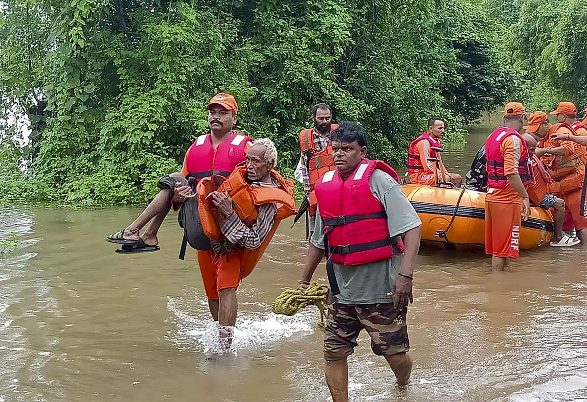 NDRF personnel rescue residents from a flooded area after heavy rains, in Narmada district. 