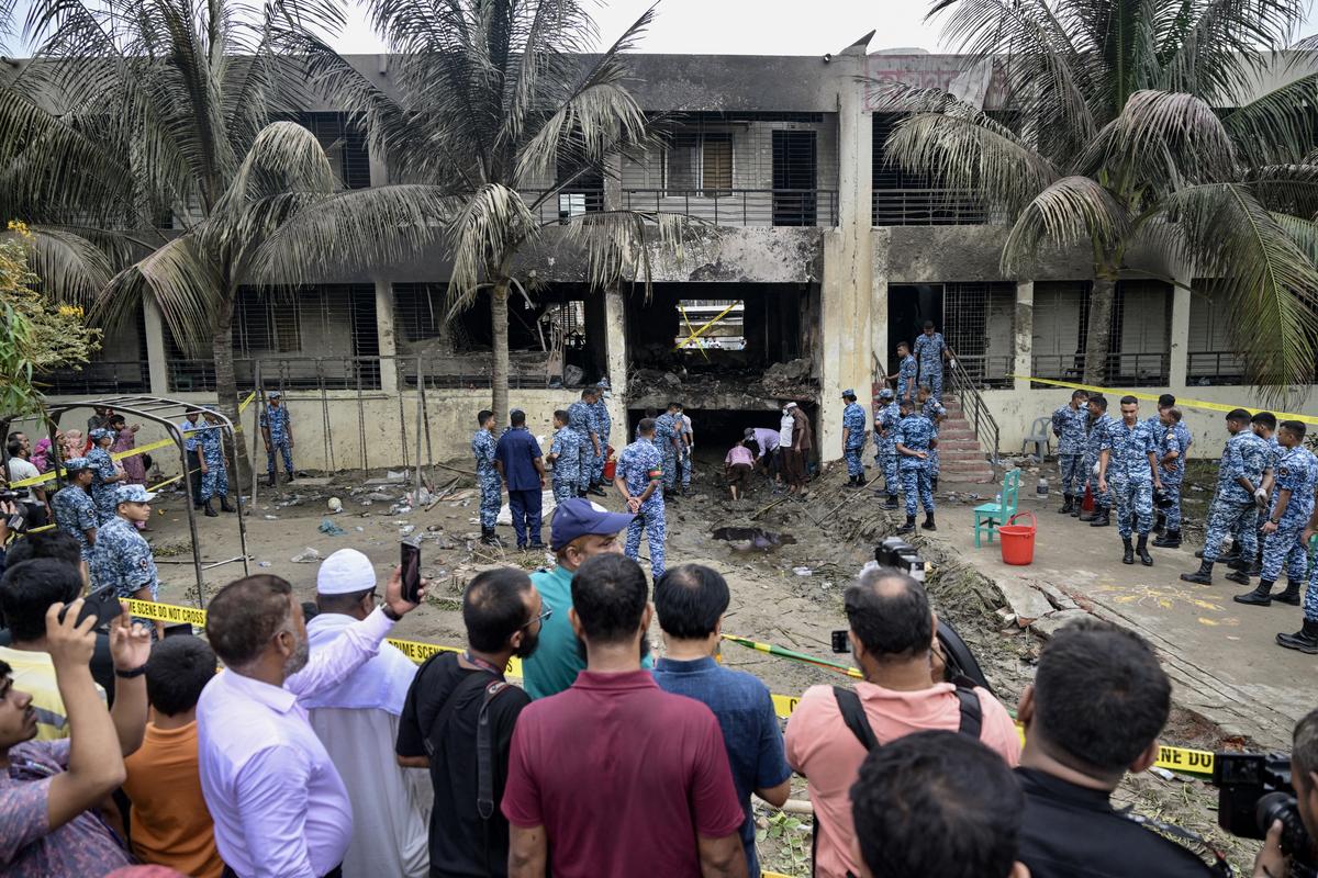 Onlookers gathered as Bangladesh Air Force personnel inspect the crash site a day after a training jet crashed into a school in Dhaka on July 22, 2025. Onlookers gathered as Bangladesh Air Force personnel inspect the crash site a day after a training jet crashed into a school in Dhaka on July 22, 2025.