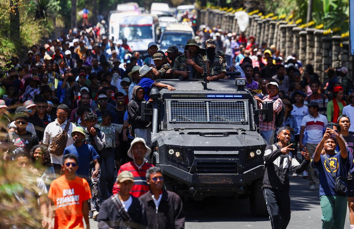 Protesters march alongside a Madagascar military vehicle during a nationwide youth-led protest over frequent power outages and water shortages, in Antananarivo, Madagascar, on October 13, 2025.