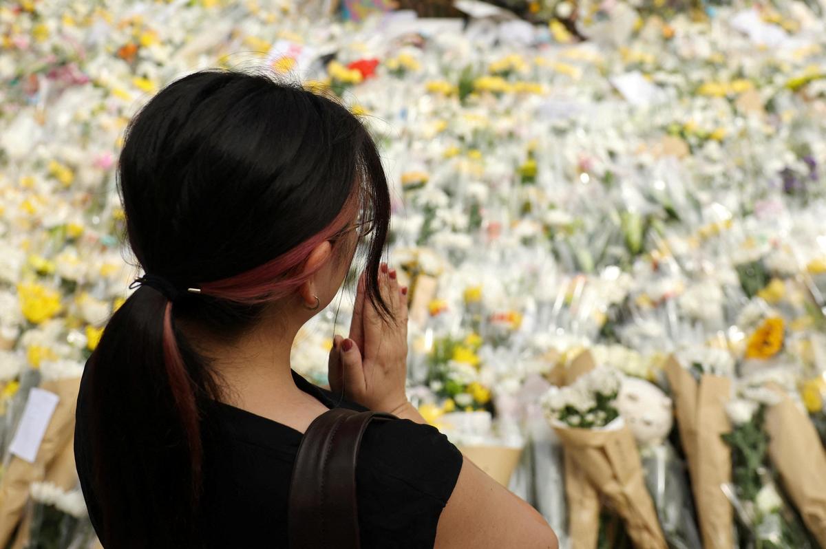 A woman pays tribute at a makeshift memorial with flower tributes for victims of the deadly fire on Wednesday, near the Wang Fuk Court housing complex in Tai Po, Hong Kong, China December 1, 2025. 