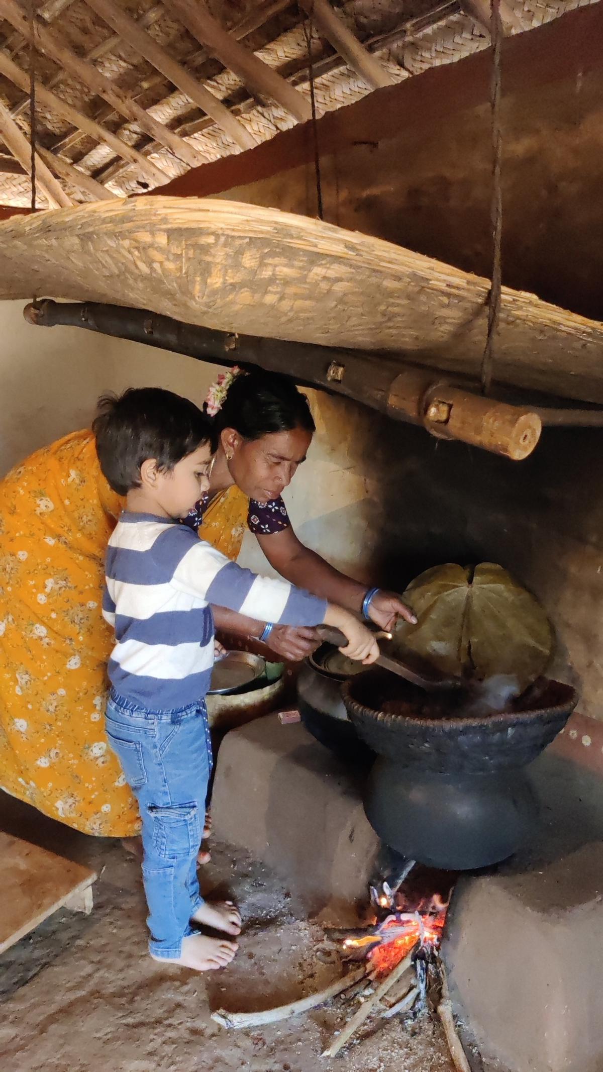 An adivasi woman helps a boy to cook in traditional style at Giri Grama Darshini at Pedalabudu near Araku, 130 kilometres from Visakhapatnam.
