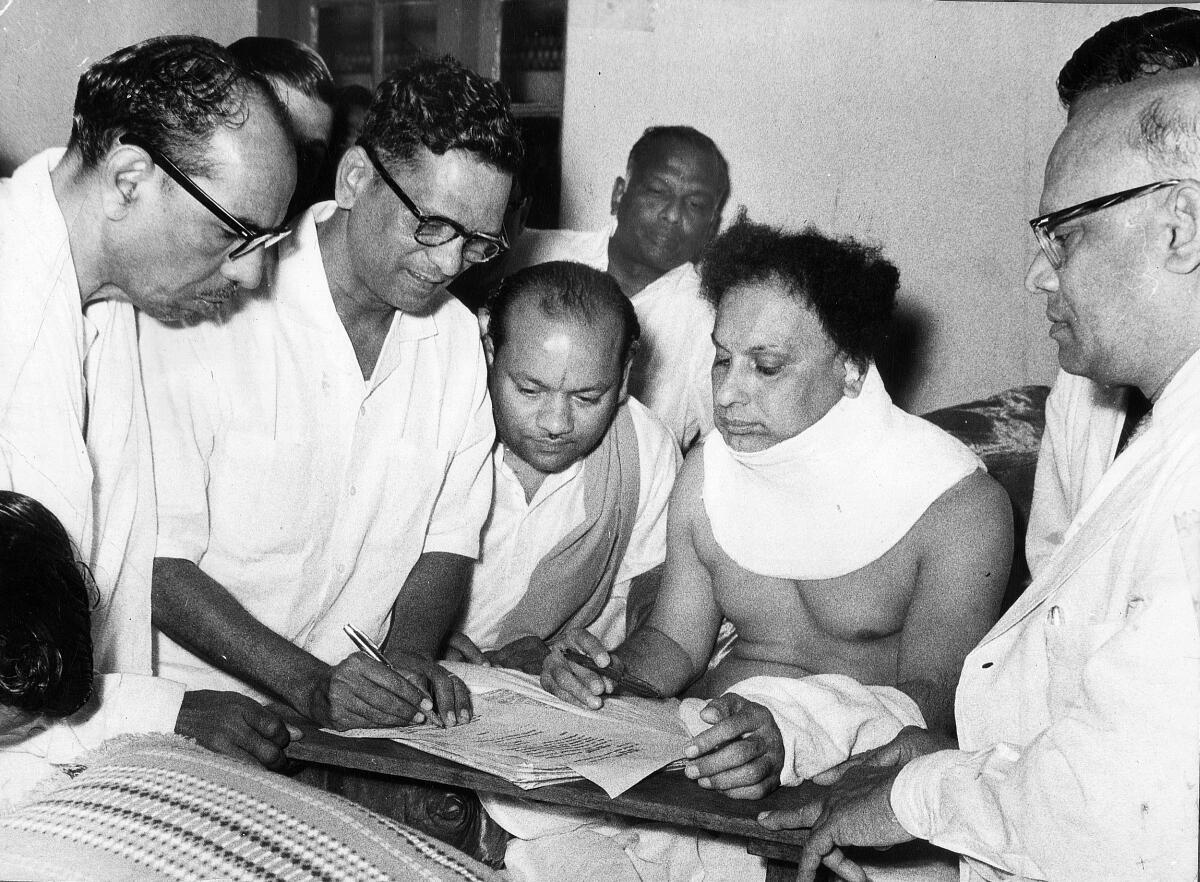 Partymen helping M.G. Ramachandran (MGR) who is recovering in hospital from gunshot wounds prepare his nomination papers for the 1967 Assembly elections a few days after M.R. Radha shot him in the neck.