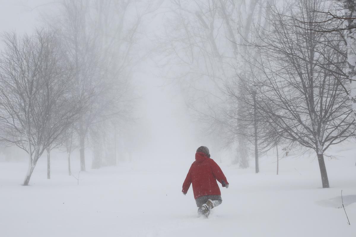 A person walks on the street as a winter storm rolls through Western New York on December 24, 2022, in Amherst N.Y. A battering winter storm has knocked out power to hundreds of thousands of homes.