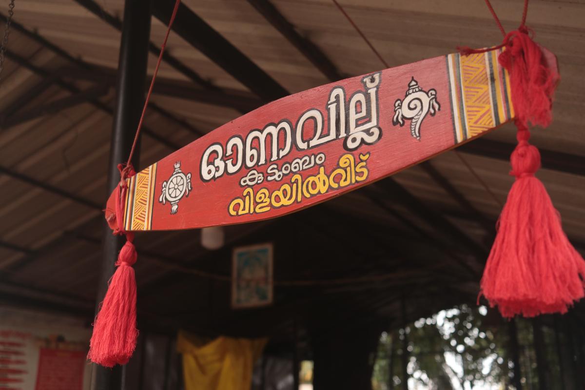 A wooden board shaped like an Onavillu indicates the residence of the Vilayilveedu family at Karamana. 