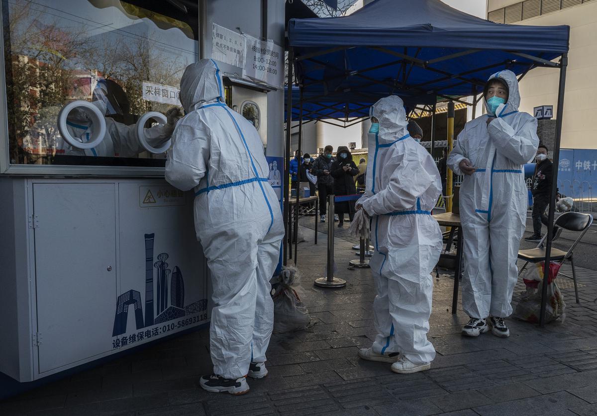 An epidemic control workers wearing PPE is given a nucleic acid test to detect COVID-19 as others line up behind her at a public testing site on December 4, 2022 in Beijing, China. 