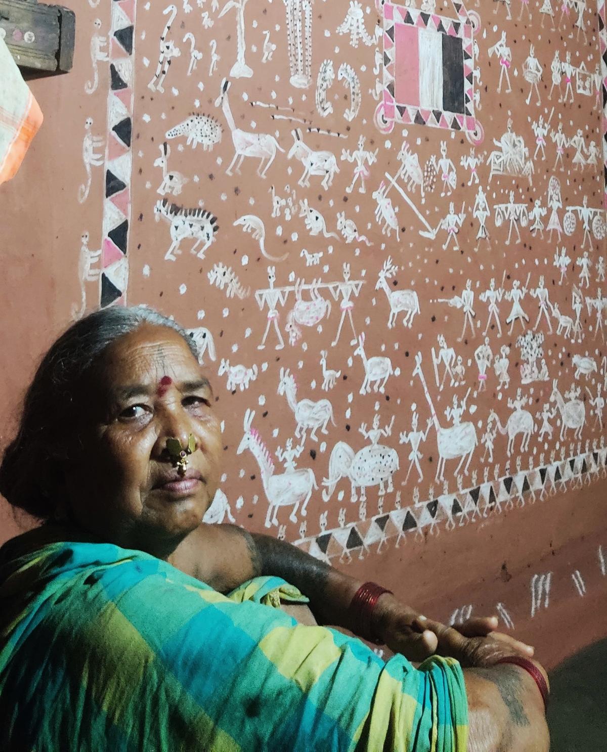 A Savara tribeswoman beside the Edisinge wall art inside her house at Seethampeta Agency. The wall art depicts her tribes association with nature.