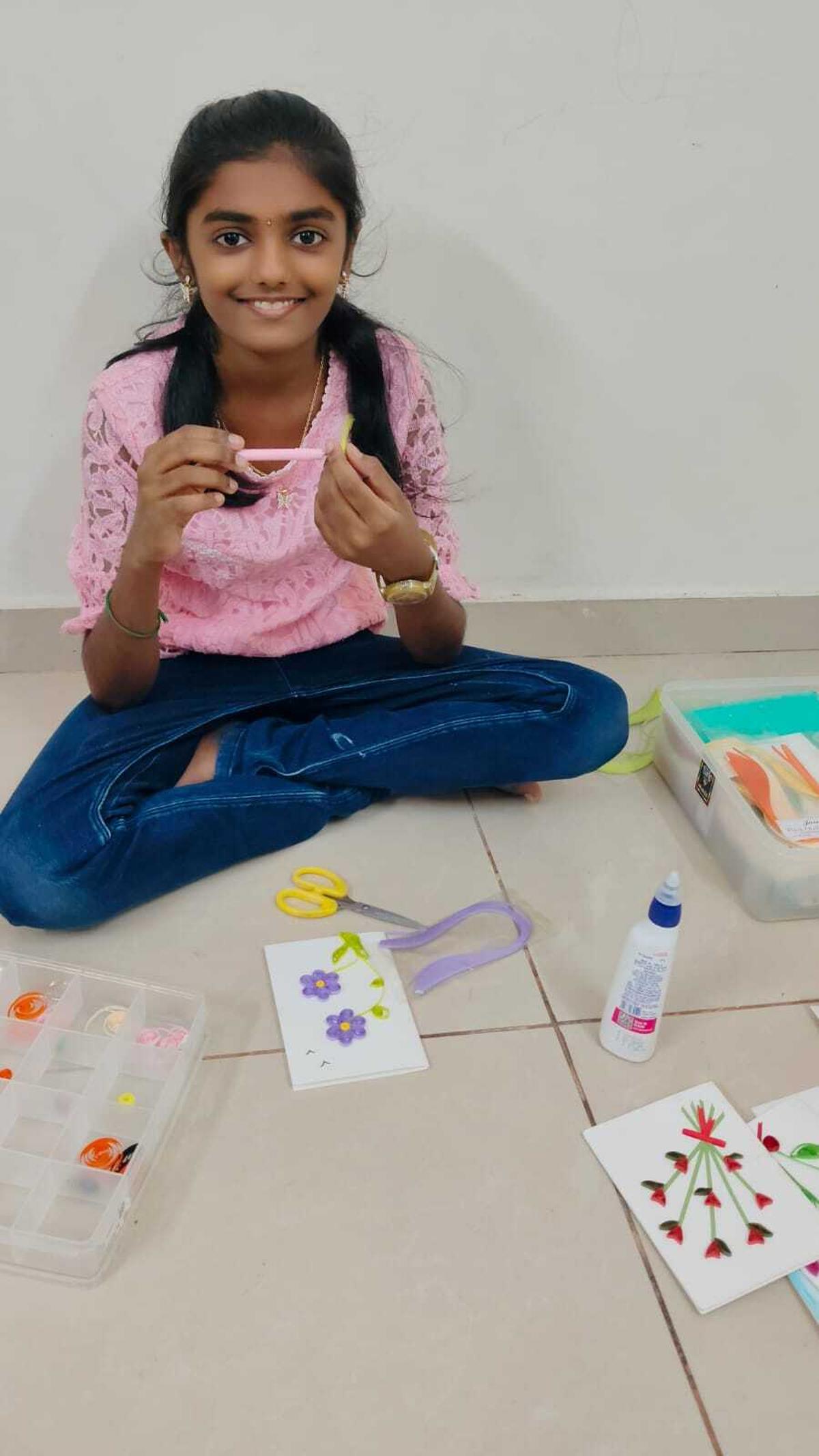 Kavya Aravind di tempat kerja; anak berusia 11 tahun membuat kartu ucapan khusus dengan kertas berlapis. 