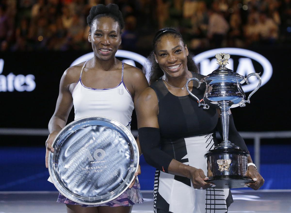 Serena Williams, right, and her sister, Venus, hold their trophies after Serena won the women’s singles final at the Australian Open.  