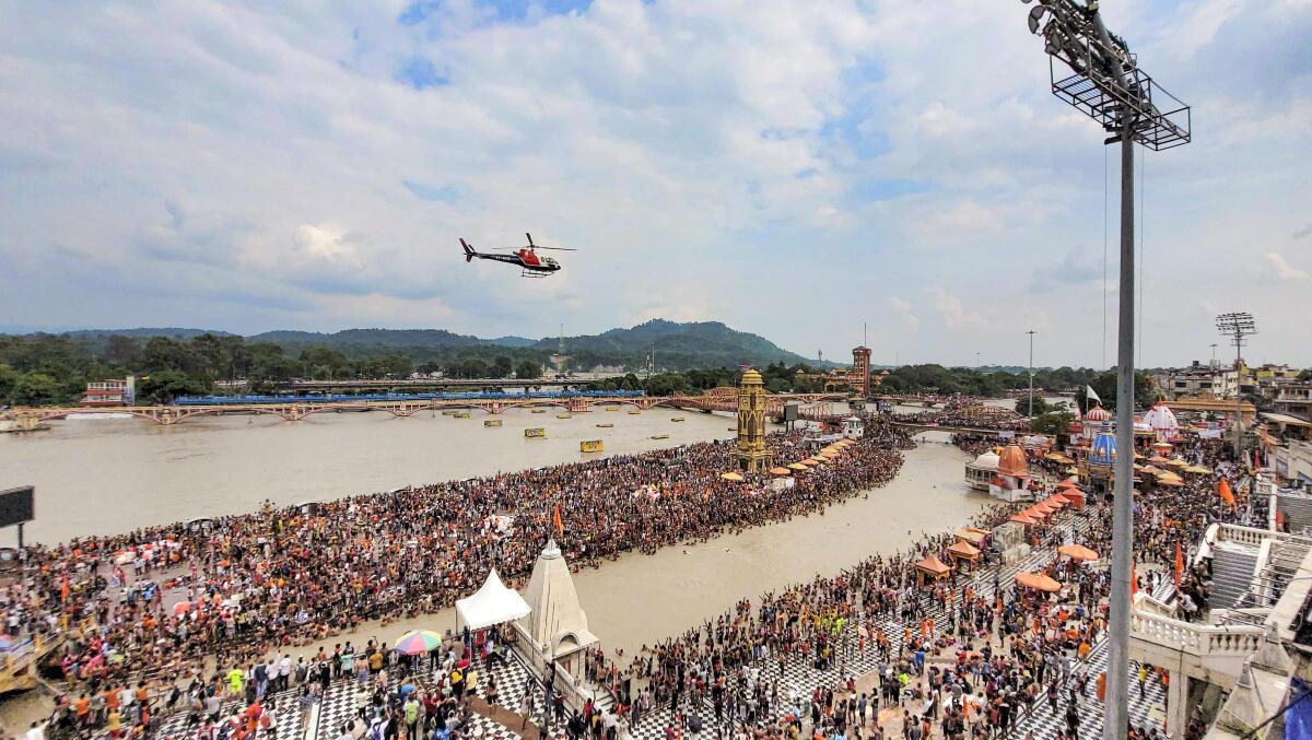 A helicopter showers flower petals on Kanwariyas who came to Har Ki Pauri Ghat to collect holy water from the Ganga river during ‘Kanwar Yatra’ in the holy month of Shravan, in Haridwar, on Tuesday, July 30, 2024. 