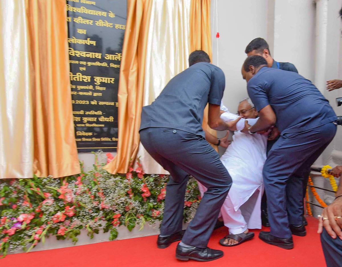 Security personnel lift up Bihar Chief Minister Nitish Kumar after he fell during the inauguration of the Wheeler Senate House of Patna University, in Patna.
