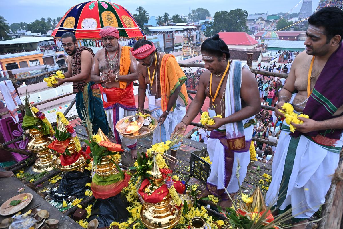 Priests perform deeparadhana to the consecrated kalasams atop Aathi Kumbeshwarar Temple during the Maha Kumbabhishekam ceremony in Kumbakonam on Monday. 