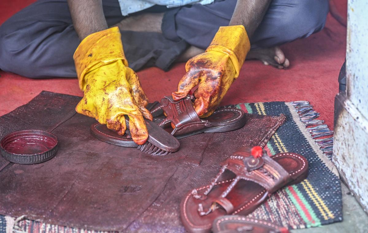 An artisan polishes a kolhapuri chappal inside a store in Chappal market in Kolhapur