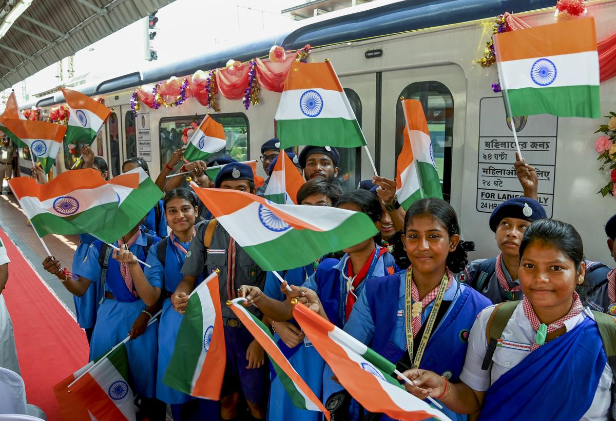 Students wave the Indian tricolour during the flag-off Ceremony of the first air-conditioned emu train of Eastern Railway at the Sealdah Station in Kolkata on August 10.