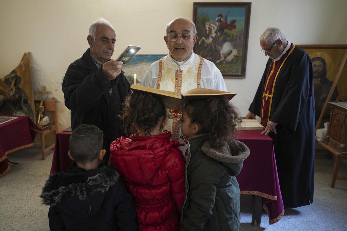 Priest Maurice el Khoury, centre, leads the Sunday Mass inside a room that is usually used as a residence for visiting bishops next to his St. George Melkite Catholic church that was destroyed by Israeli airstrike, in the town of Dardghaya in southern Lebanon, on December 22, 2024.