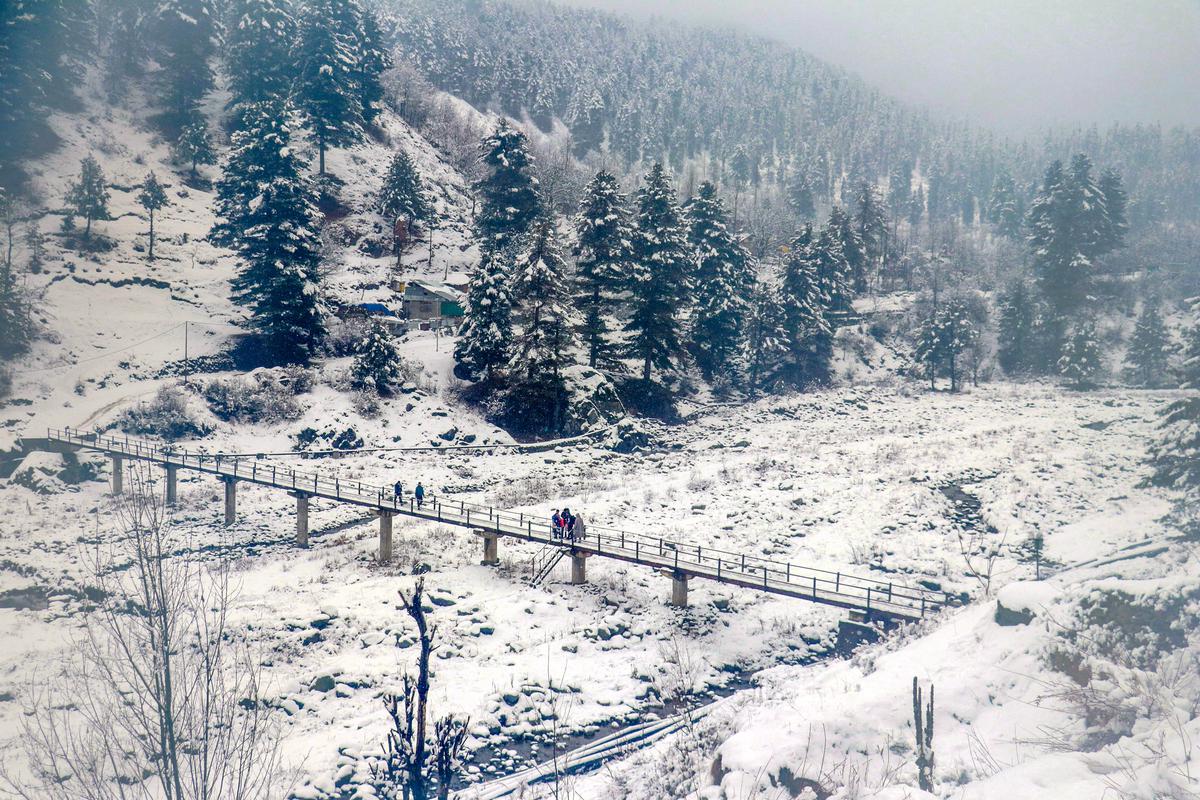 People walk on a bridge amid fresh snowfall, at Tangmarg area of north Kashmir.