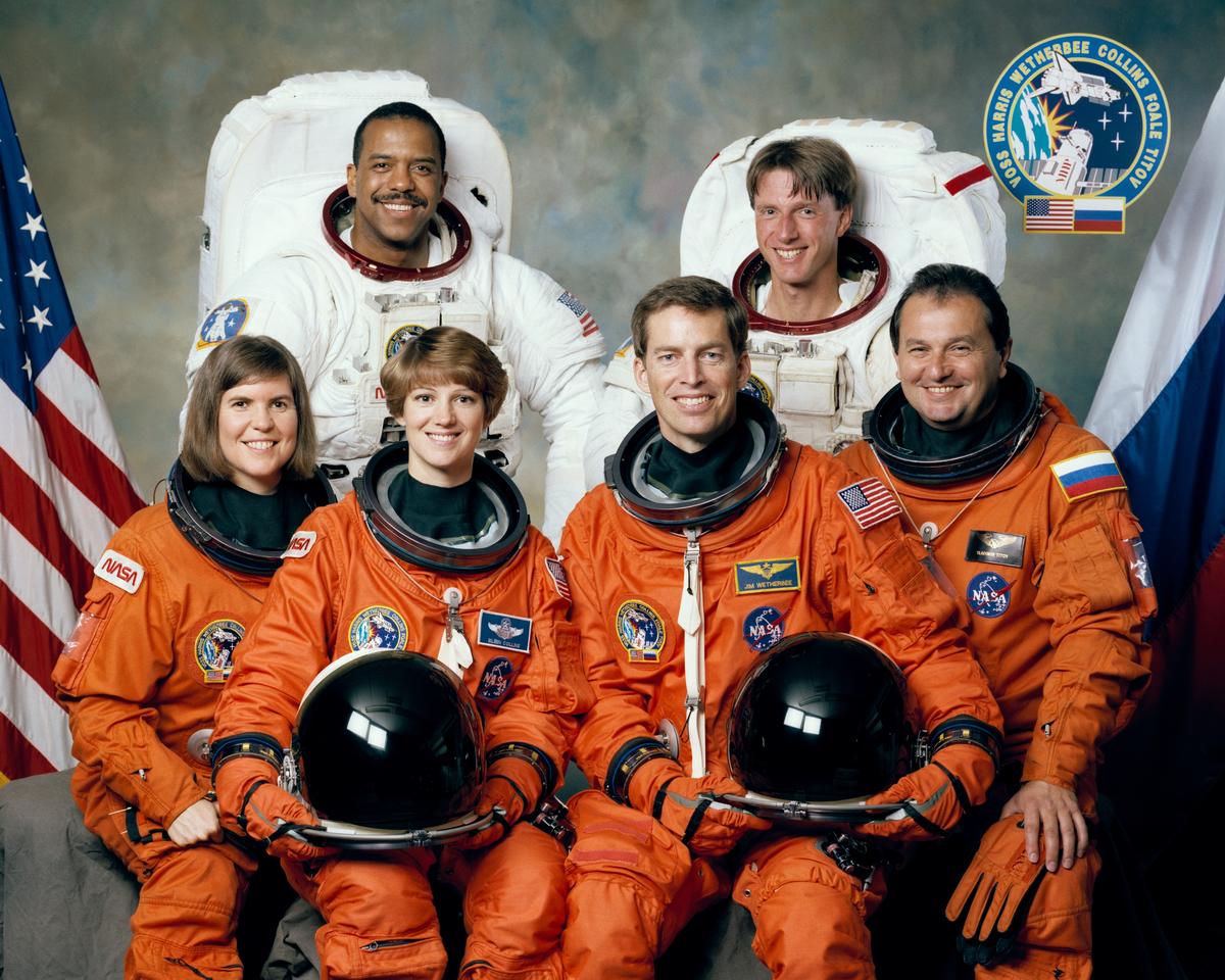 With the U.S. and Russian flags in the background, five NASA astronauts and a Russian cosmonaut named to fly aboard the Space Shuttle Discovery for the mission pose for the flight crew portrait at the Johnson Space Center (JSC). Left to right (front row) are Janice Voss, mission specialist; Eileen Collins, pilot; James Wetherbee, mission commander; and Vladimir Titov of the Russian Space Agency (RSA), mission specialist. In the rear are Bernard Harris Jr., payload commander; and Michael Foale, mission specialist.