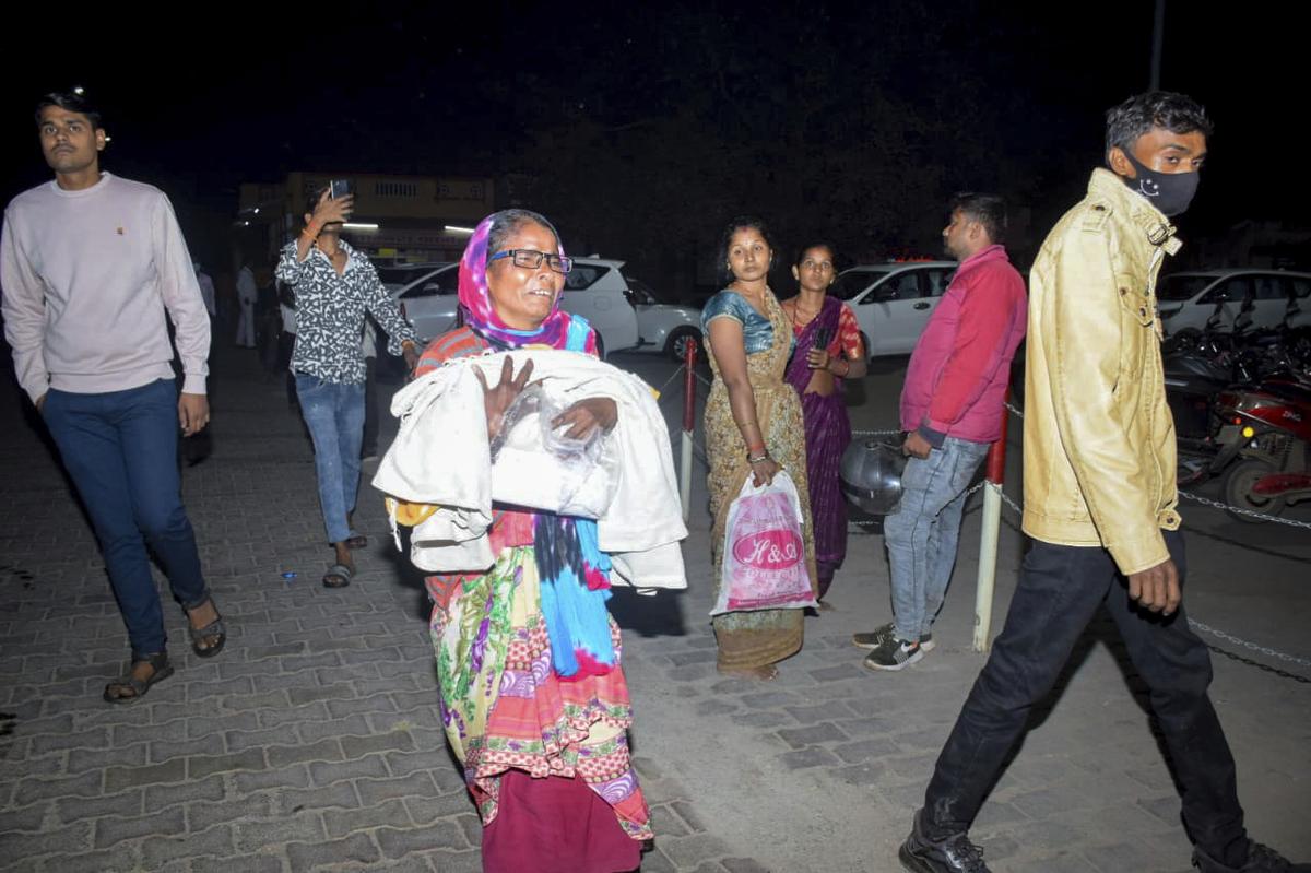 A woman rushes a child to the emergency ward after a fire broke out in a neonatal intensive care unit at Jhansi Medical College hospital in Jhansi, on November 15, 2024. 