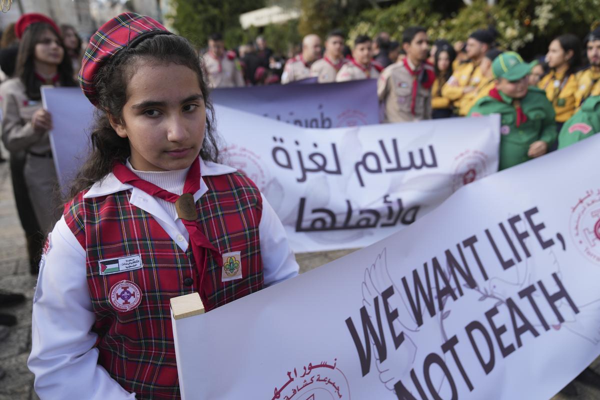 Palestinian scouts carry posters, one reads “Peace for Gaza and its people,” while they march during Christmas Eve celebrations at the Church of the Nativity, traditionally recognized by Christians to be the birthplace of Jesus Christ, in the West Bank city of Bethlehem on December 24, 2024.