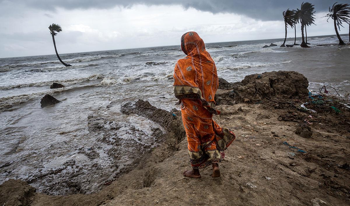 A woman is standing in front of her house which is under water due to tidal flood in Mousuni Island, Sundarbans. A woman is standing in front of her house which is under water due to tidal flood in Mousuni Island, Sundarbans.
