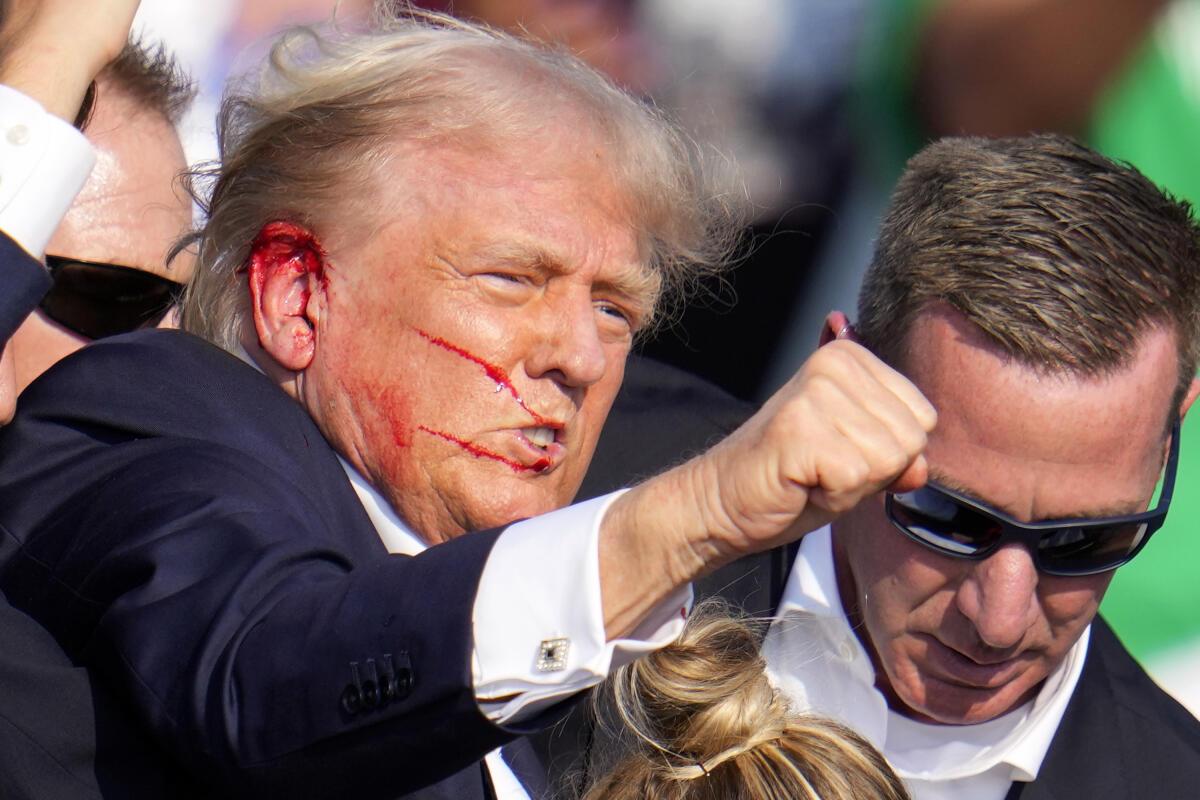 Donald Trump shows his fist as he is rushed offstage by U.S. Secret Service agents.